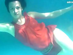 Girl in a red dress swims underwater